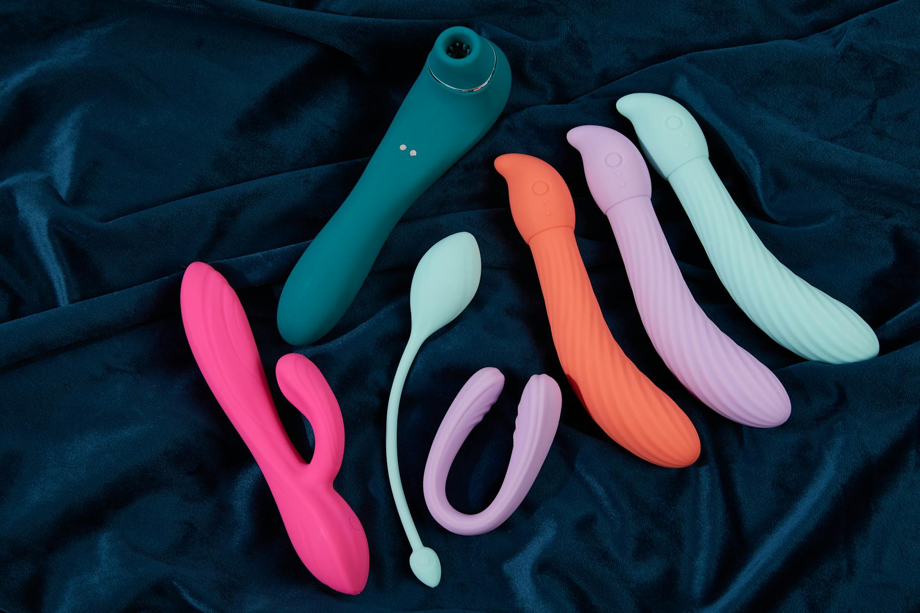 Sininen silikonivibraattori käsissä violetilla taustalla, modernin intimiteetin symboli