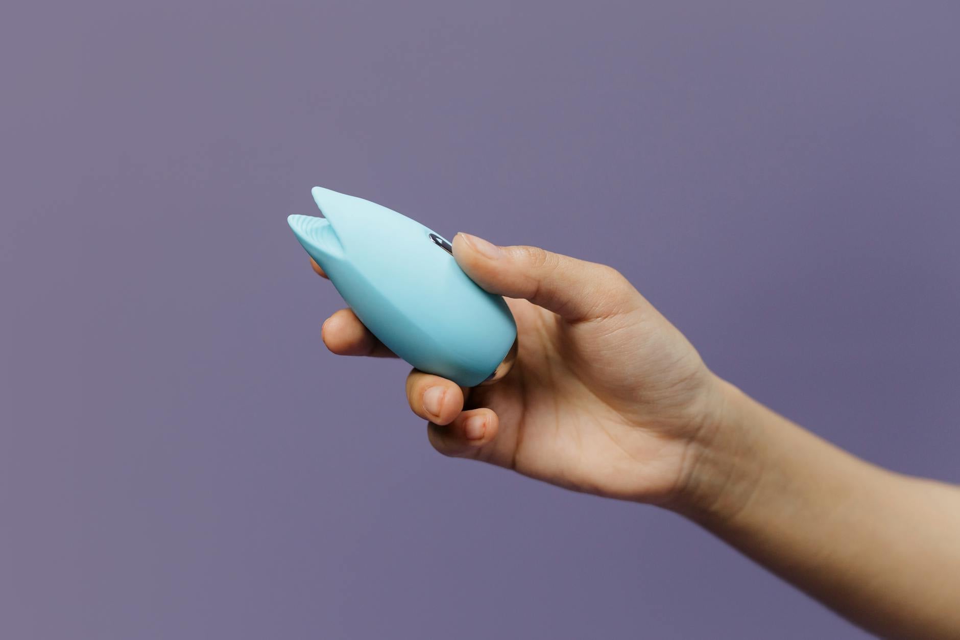Sininen silikoninen Lem vibrator kädessä violetilla taustalla, joka edustaa itserakkautta ja seksuaalisuutta
